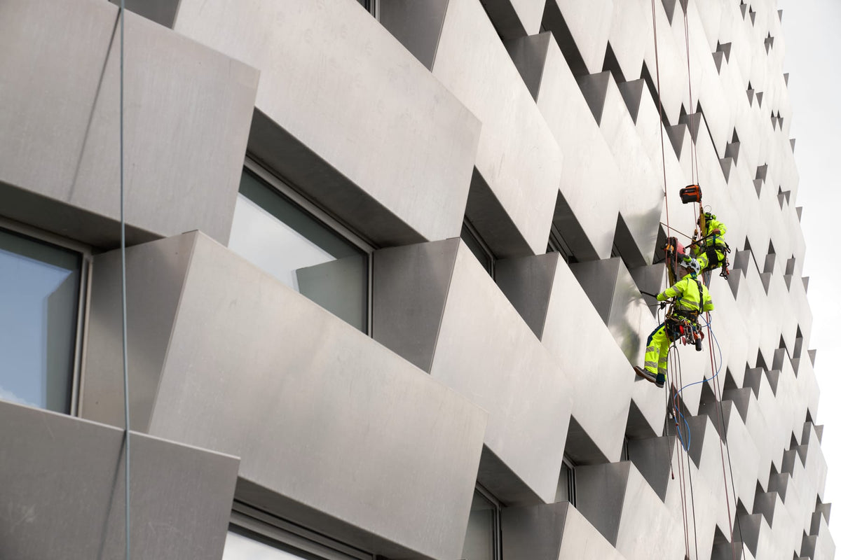 Industriekletterer in gelber MASCOT-Warnschutzkleidung an einer Hausfassade